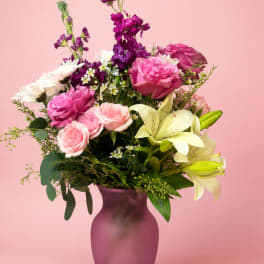 Pink and purple bouquet with lilies and roses in a purple vase