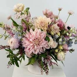 Pastel floral arrangement in a white vase with pink and cream blooms