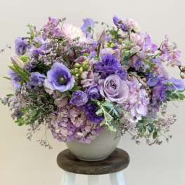 Lavender and purple floral arrangement in a white vase