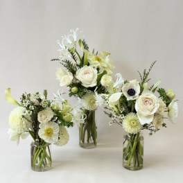 Three white floral arrangements in clear glass vases