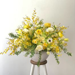 Large yellow and white floral arrangement in a white vase