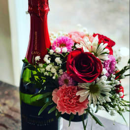 Red champagne bottle with a small bouquet of pink and white flowers