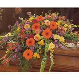 Colorful casket spray with orange gerbera daisies and yellow blooms