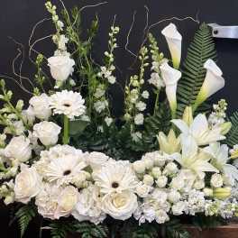 White floral arrangement with roses, gerbera daisies, lilies, and calla lilies