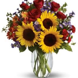 Bouquet of sunflowers and red roses in a clear glass vase