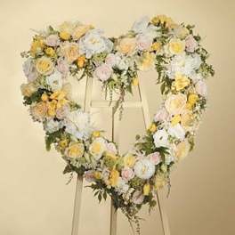 Heart-shaped floral wreath on an easel with pastel roses and white blooms