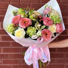 Bouquet of pink and cream flowers wrapped in pale paper with a ribbon