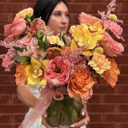 Colorful bouquet of roses, orchids, and carnations in a glass vase