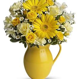 Yellow and white flower arrangement in a yellow pitcher vase
