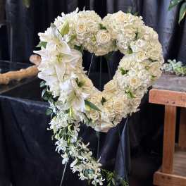 White floral heart-shaped funeral wreath with cascading orchids