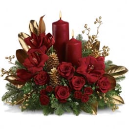 Red roses with candles and gold accents in a holiday centerpiece