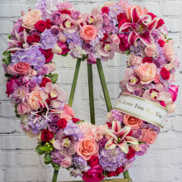 Heart-shaped floral wreath on an easel with pink, purple, and white blooms