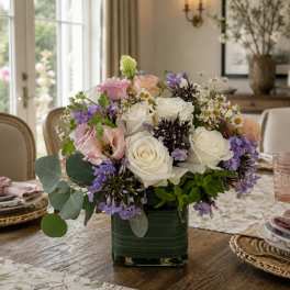 Mixed bouquet of white, pink, and purple flowers in a green glass vase