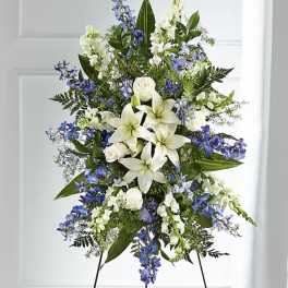 Standing floral spray with white lilies, roses, and blue flowers