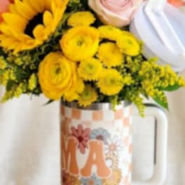 Bouquet of yellow and pink flowers in a decorative mug vase