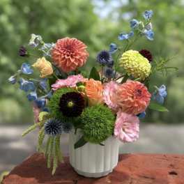 Colorful mixed bouquet in a white vase with dahlias and other blooms