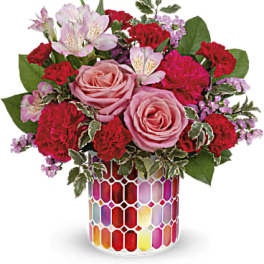 Pink roses and red carnations in a colorful mosaic vase