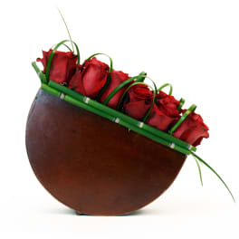 Red roses arranged in a curved brown container