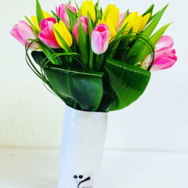 Bouquet of pink and yellow tulips in a white vase