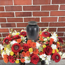 Red, orange, and white floral urn arrangement around a black vase