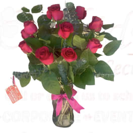 Bouquet of red roses in a glass vase with a pink ribbon