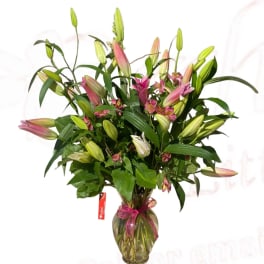 Bouquet of pink lilies in a glass vase with a ribbon
