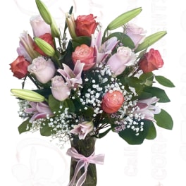 Bouquet of pink roses and lilies in a glass vase with a ribbon