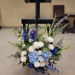 Blue and white floral arrangement with tall stems in a vase