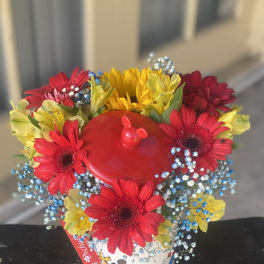 Bright mixed bouquet in a Mickey Mouse bucket with red, yellow, and blue flowers