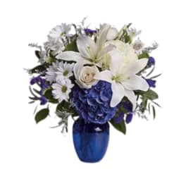 White lilies and blue flowers in a cobalt vase