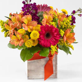 Bright mixed bouquet in a wooden box with an orange ribbon