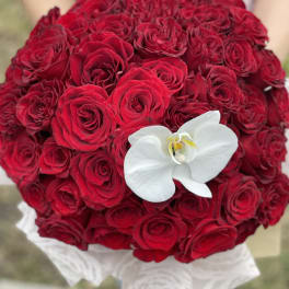 Round bouquet of red roses with a white orchid accent
