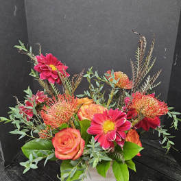 Bright pink and orange flowers arranged in a white wooden box