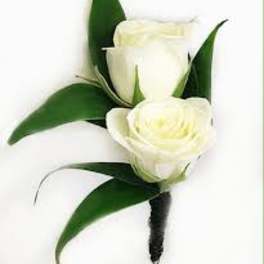 Two white rose boutonnieres with dark green leaves