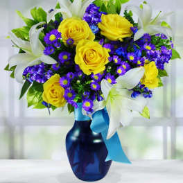 Bouquet of yellow roses, purple flowers, and white lilies in a blue vase