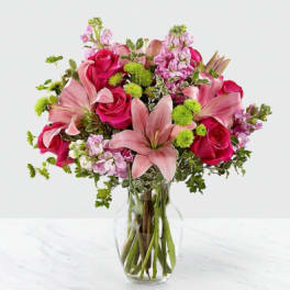 Pink roses and lilies arranged in a clear glass vase