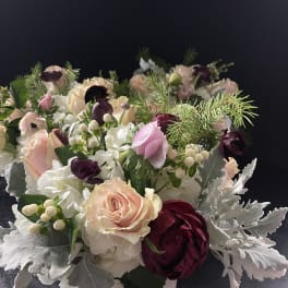 Compact floral arrangement with pink, white, and burgundy blooms in a white container