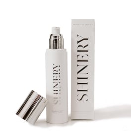 White skincare bottle with silver cap beside matching box and lid
