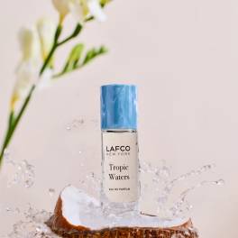 Perfume bottle on a coconut half with water splashing around it