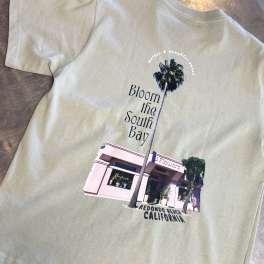 Light green T-shirt with a floral shop graphic and palm tree print
