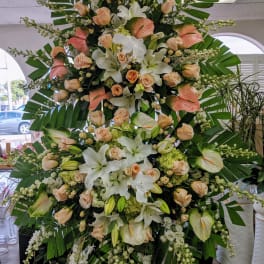 Large standing floral spray with white lilies, peach roses, and anthuriums