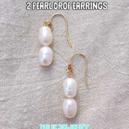 Pair of pearl drop earrings with gold hooks on a fabric background