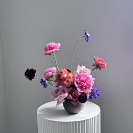 Mixed pink and purple flowers arranged in a dark vase