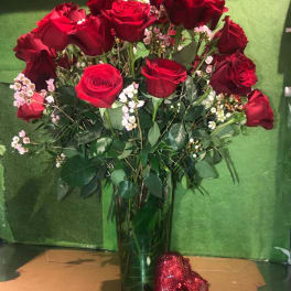 Red roses in a glass vase with a red heart decoration