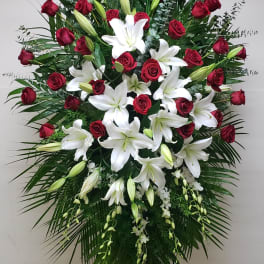 Standing floral spray with red roses and white lilies on an easel