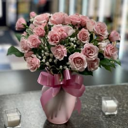 Pink roses arranged in a pink vase with a ribbon bow