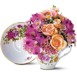 Bouquet of peach roses and pink flowers in a floral teacup
