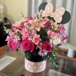 Pink and peach flower arrangement in a polka-dot box with a butterfly topper