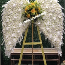 Standing angel wing spray of white flowers with yellow and green bouquet center on wooden easel