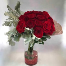 Red rose bouquet in a clear glass vase with silvery foliage